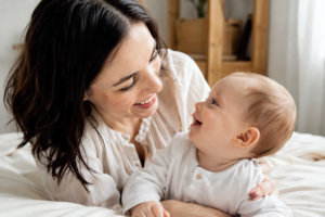 Bébé et mère en interaction, regard et sourire, ambiance chaleureuse, lumière naturelle